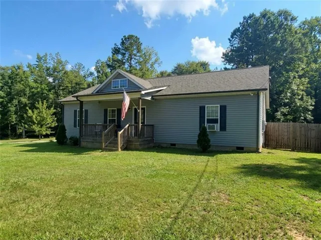 Gray siding exterior with a partial wooden fence, front porch with wood railings, and a dormer window