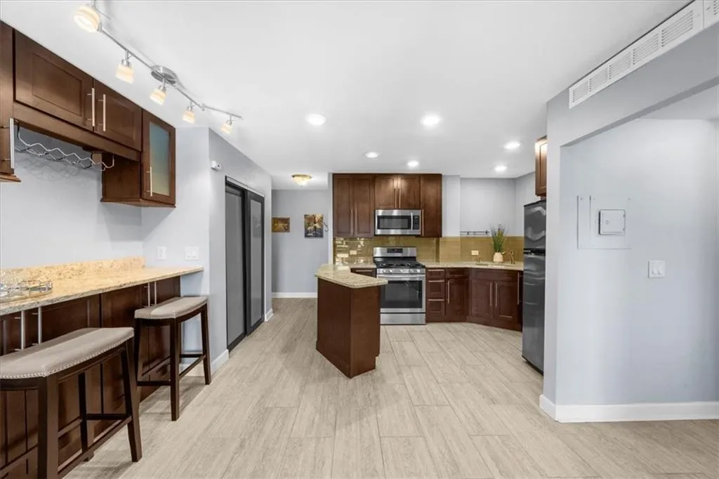 Kitchen featuring decorative backsplash, appliances with stainless steel finishes, recessed lighting, dark brown cabinetry, and light wood-type flooring