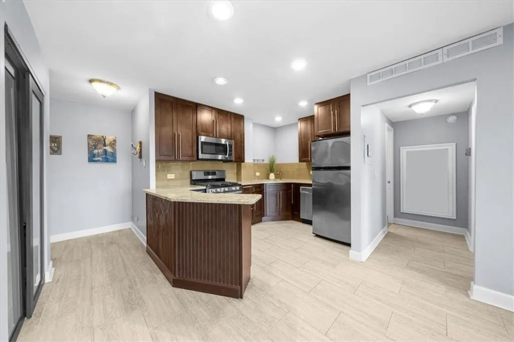 Kitchen with tasteful backsplash, a peninsula, appliances with stainless steel finishes, recessed lighting, and light wood finished floors