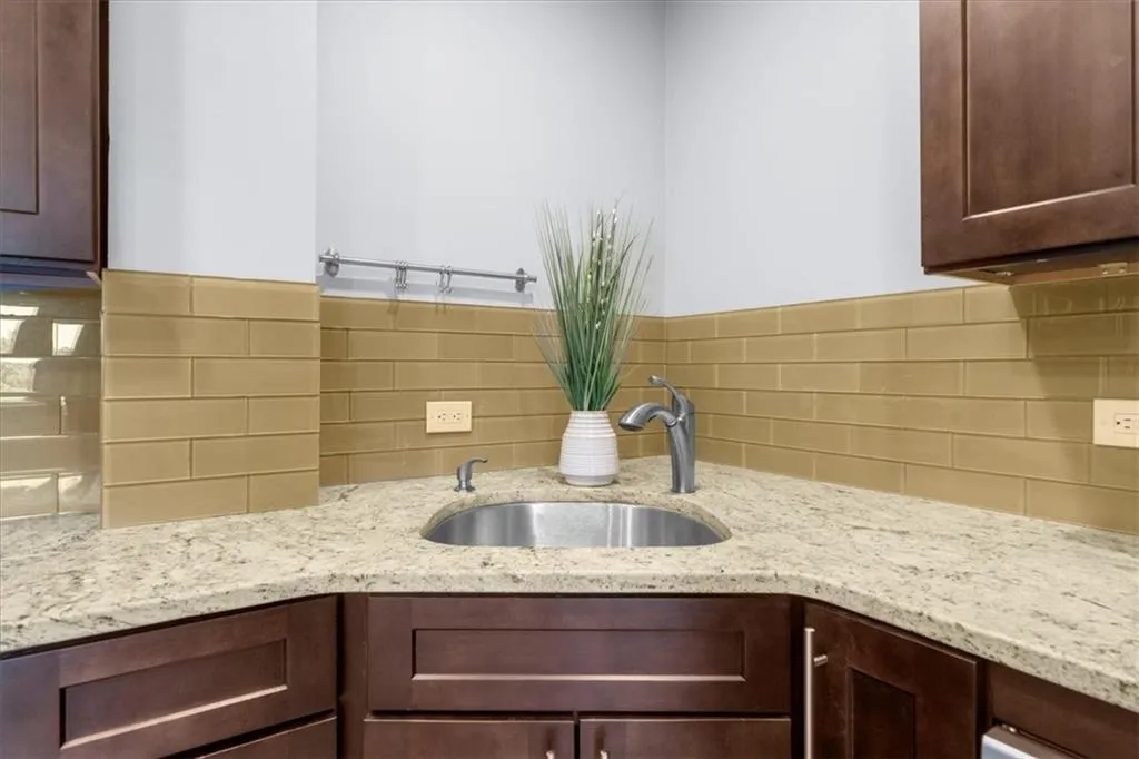 Kitchen with light stone counters, tasteful backsplash, and dark brown cabinetry