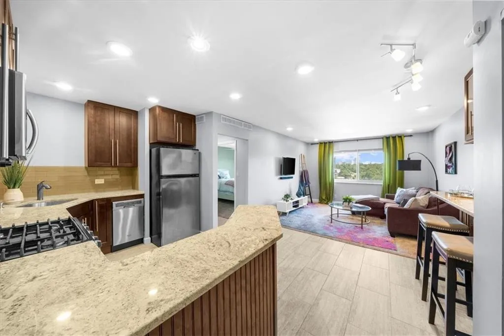 Kitchen featuring stainless steel appliances, backsplash, light stone counters, open floor plan, and recessed lighting
