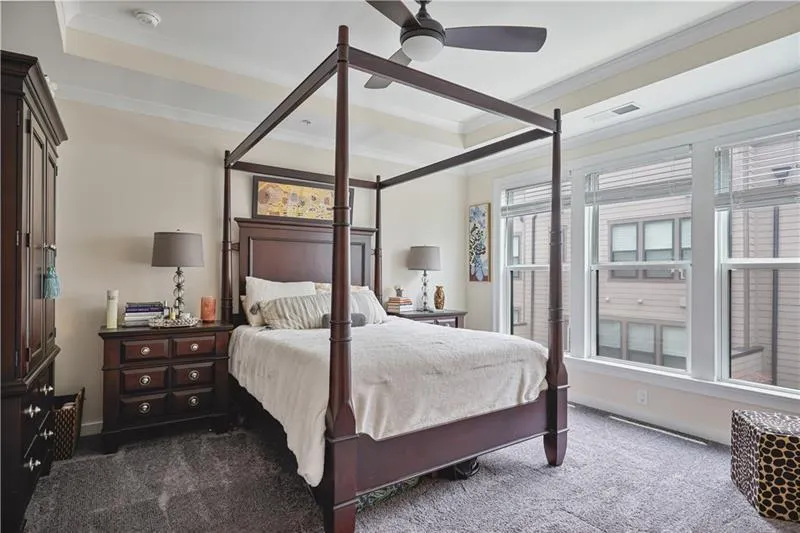 Primary bedroom with a tray ceiling, crown molding, and a ceiling fan