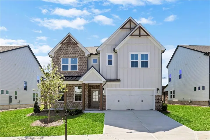 Brick and board and batten facade with gabled architectural accents, covered entry, attached garage, and concrete driveway