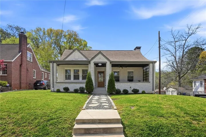 White brick exterior featuring a covered front porch with dark wood accents