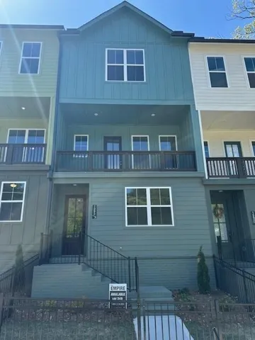 Three-story townhome featuring board and batten siding and multiple windows