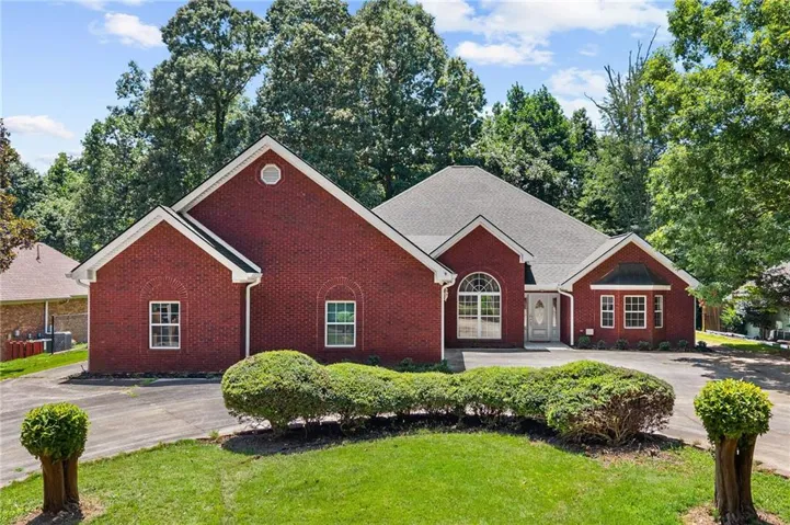 Brick exterior featuring multiple gables and a dark shingle roof