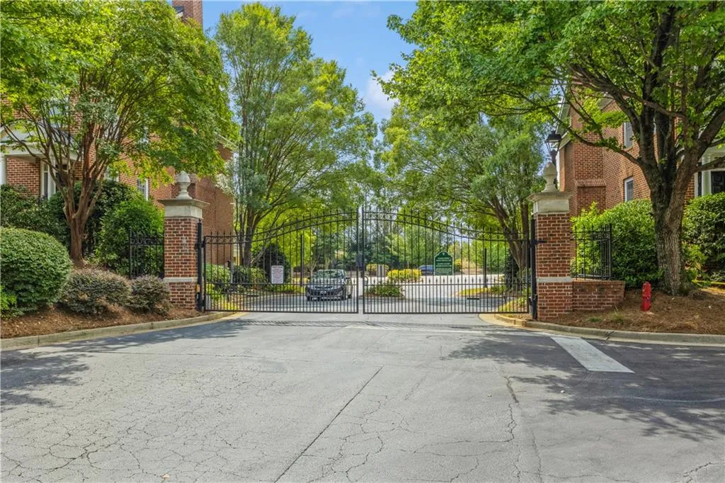 View of asphalt road featuring curbs, a gated entry, and a gate