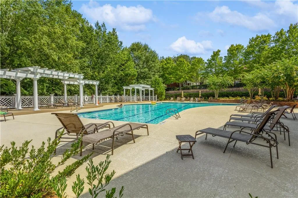 Community pool with a pergola, a patio area, and view of scattered trees