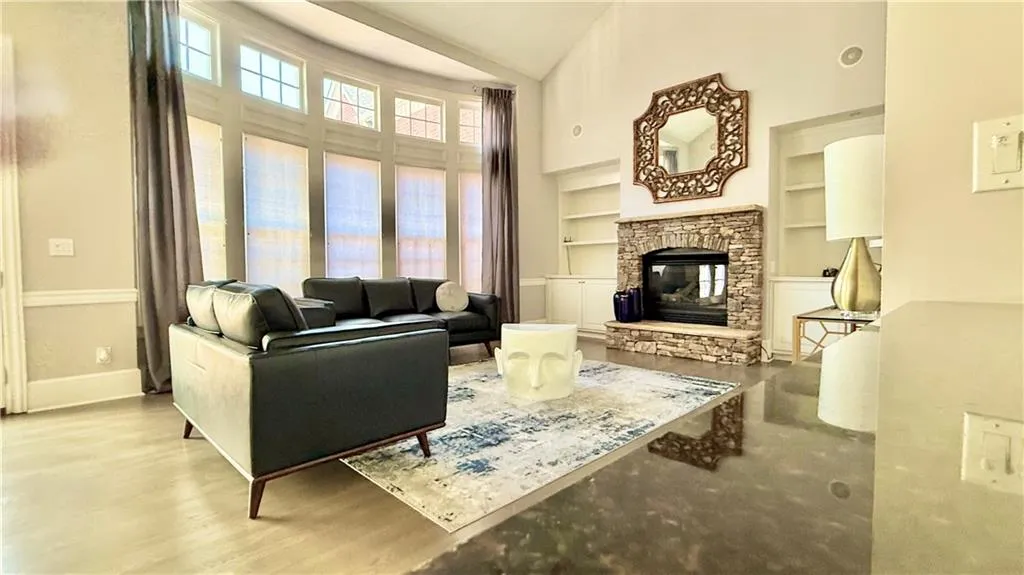 Vaulted greatroom with ceiling fan, stone fireplace, bookcases, and a fridge and bar for your breverages and stemware.