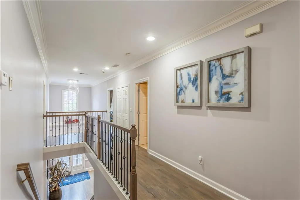Hallway with crown molding, wood finished floors, an upstairs landing, a chandelier, and recessed lighting