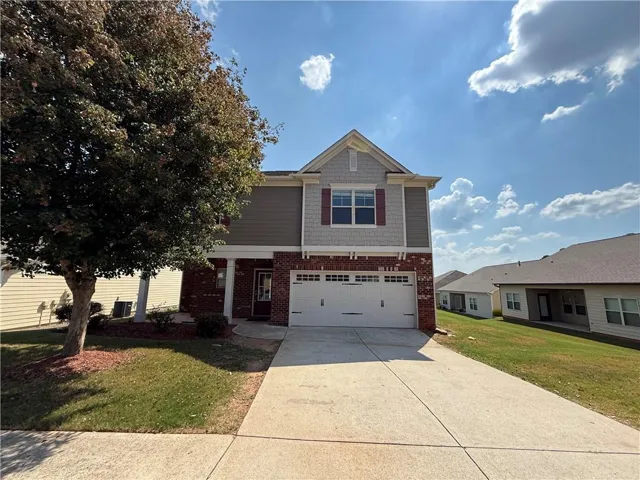 Two-story residence featuring a brick and siding exterior, an attached two-car garage, and a concrete driveway