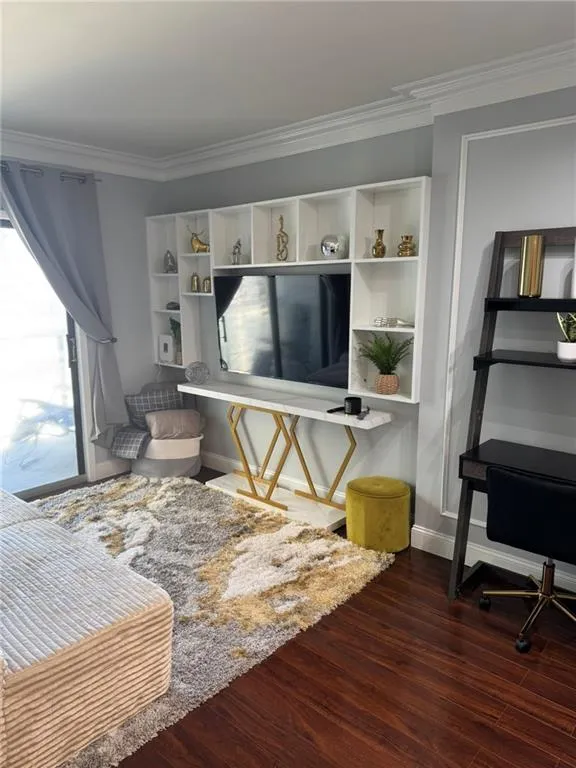 Living area featuring baseboards, crown molding, and hardwood floors