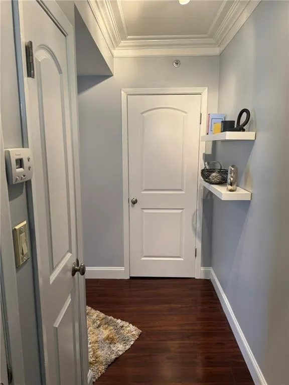 Entryway featuring baseboards, dark hardwood floors, and crown molding