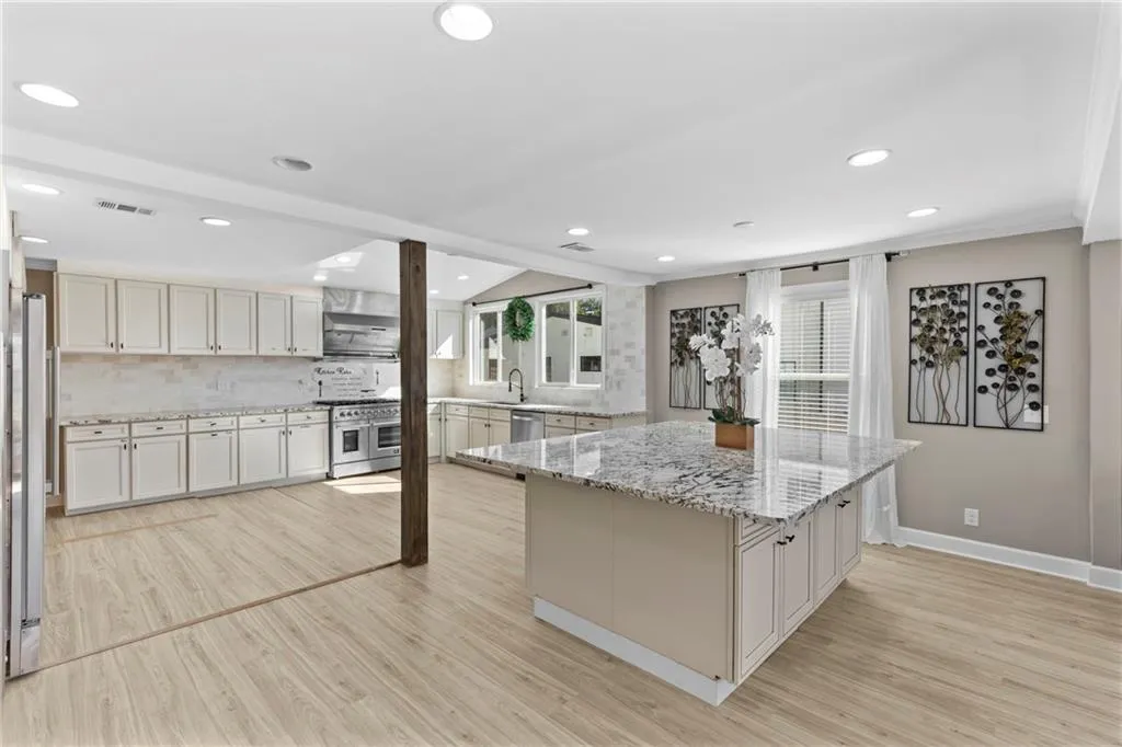 Kitchen with light stone counters, light wood-style flooring, recessed lighting, and appliances with stainless steel finishes