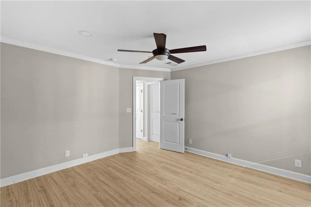 Unfurnished room with ornamental molding, light wood-style floors, and ceiling fan