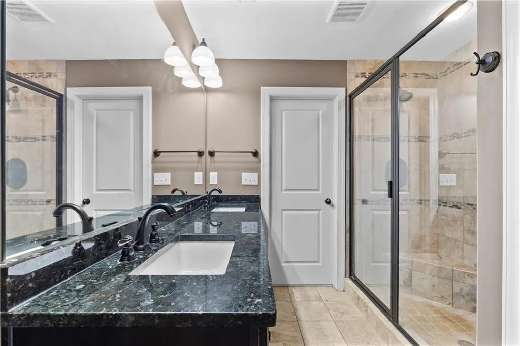 Bathroom featuring double vanity, a stall shower, and light tile patterned flooring