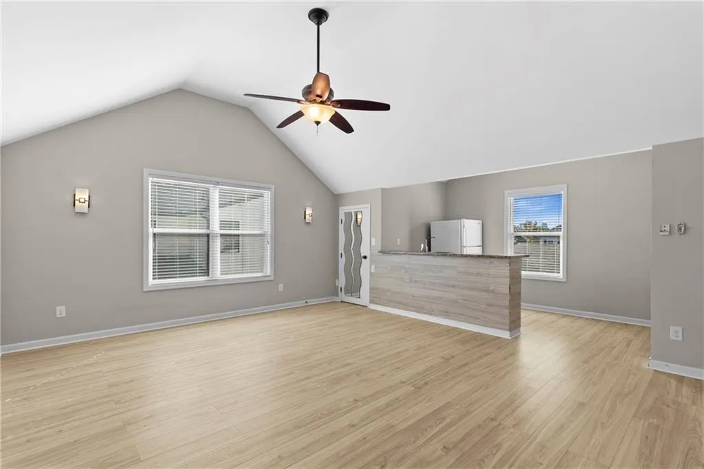 Unfurnished living room featuring lofted ceiling, light wood-style flooring, and ceiling fan