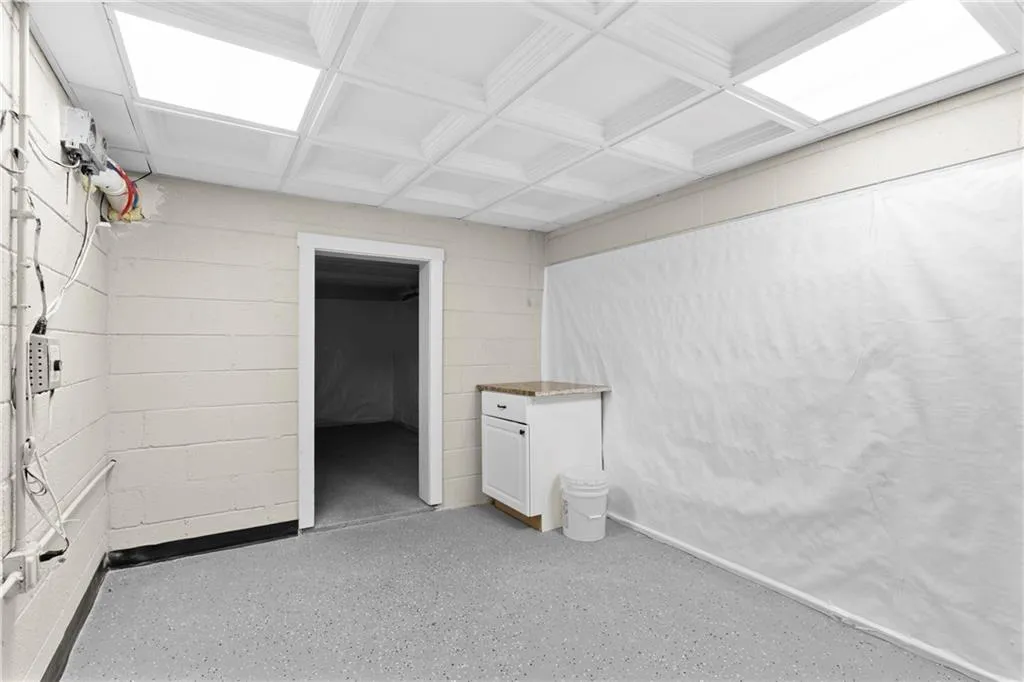Unfurnished bedroom featuring concrete block wall, coffered ceiling, and beamed ceiling