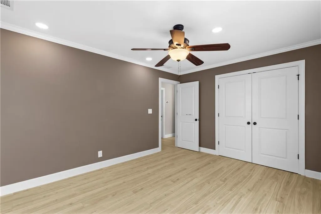 Unfurnished bedroom featuring ornamental molding, light wood-style floors, recessed lighting, ceiling fan, and a closet