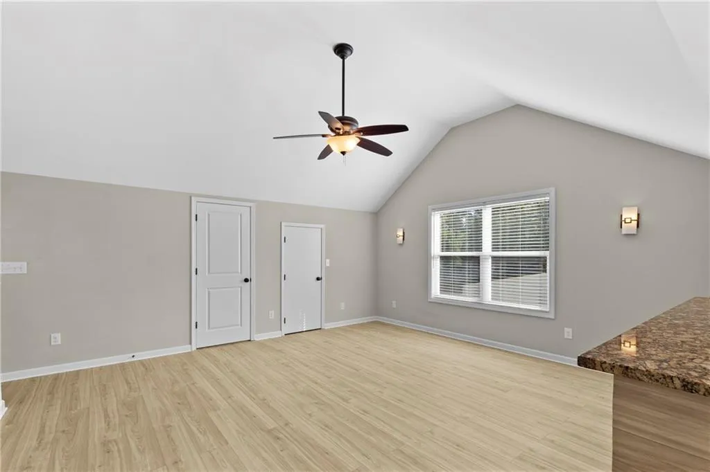 Unfurnished living room with light wood-type flooring, lofted ceiling, and a ceiling fan