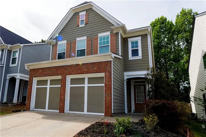 Two-story residence featuring a brick facade on the lower level and horizontal siding on the upper