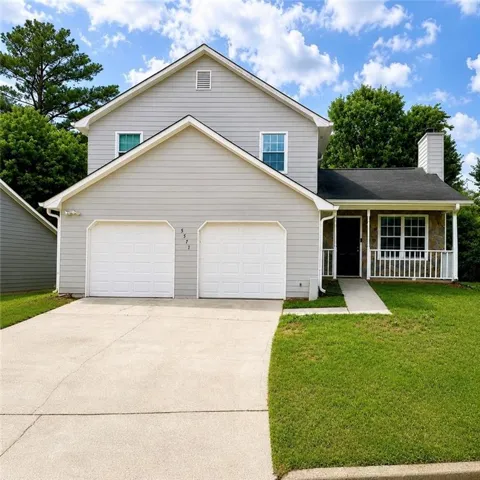 Two-story property featuring light grey siding and a two-car garage