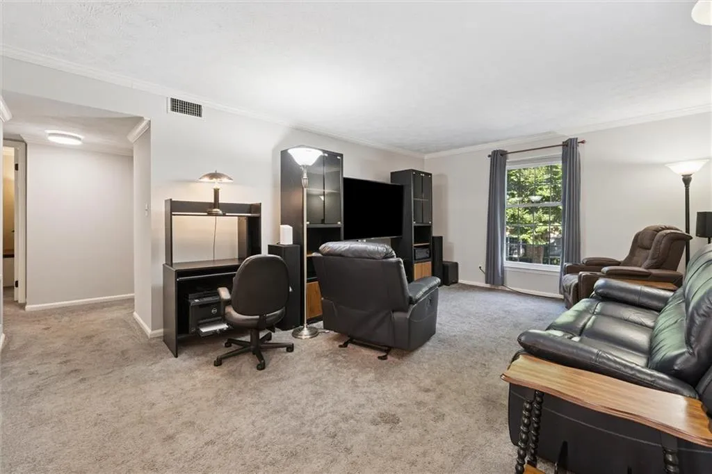 Living room with crown molding, light colored carpet, a textured ceiling, and a desk