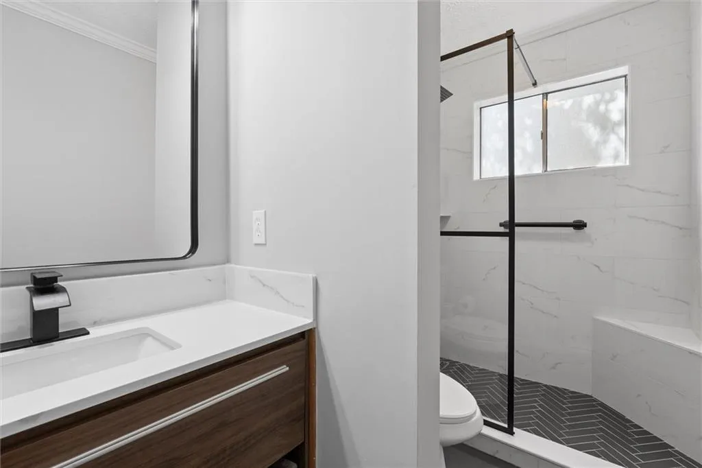 Full bath with vanity, a marble finish shower, and ornamental molding