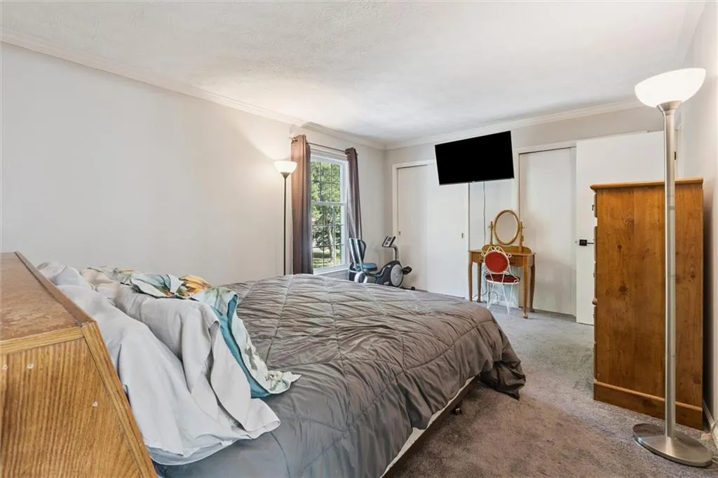 Bedroom featuring carpet, ornamental molding, multiple closets, and a textured ceiling