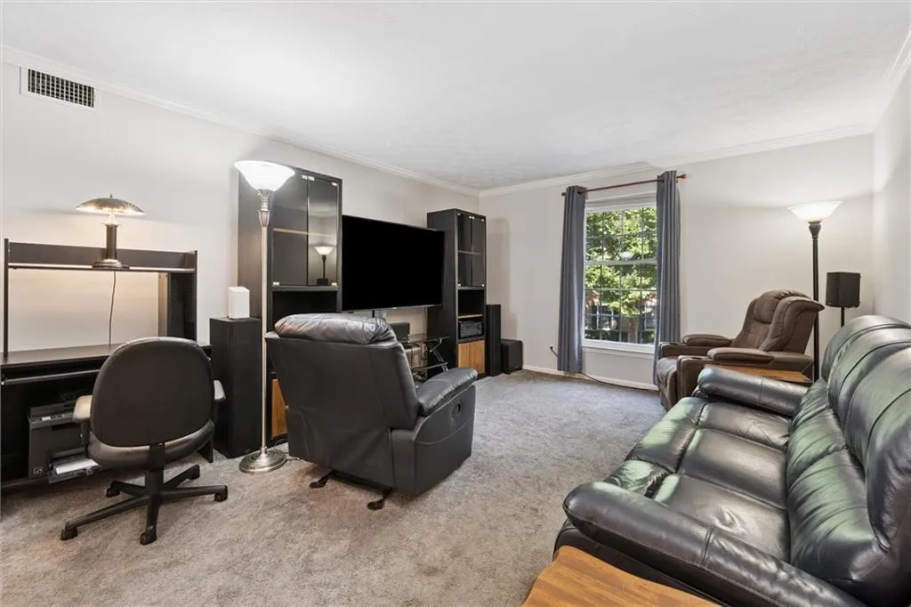 Living room with crown molding, carpet flooring, and a desk