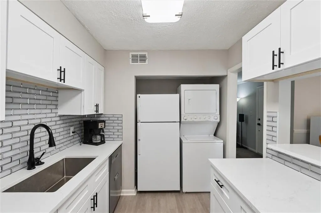 Kitchen with white cabinetry, freestanding refrigerator, a textured ceiling, light wood finished floors, and backsplash