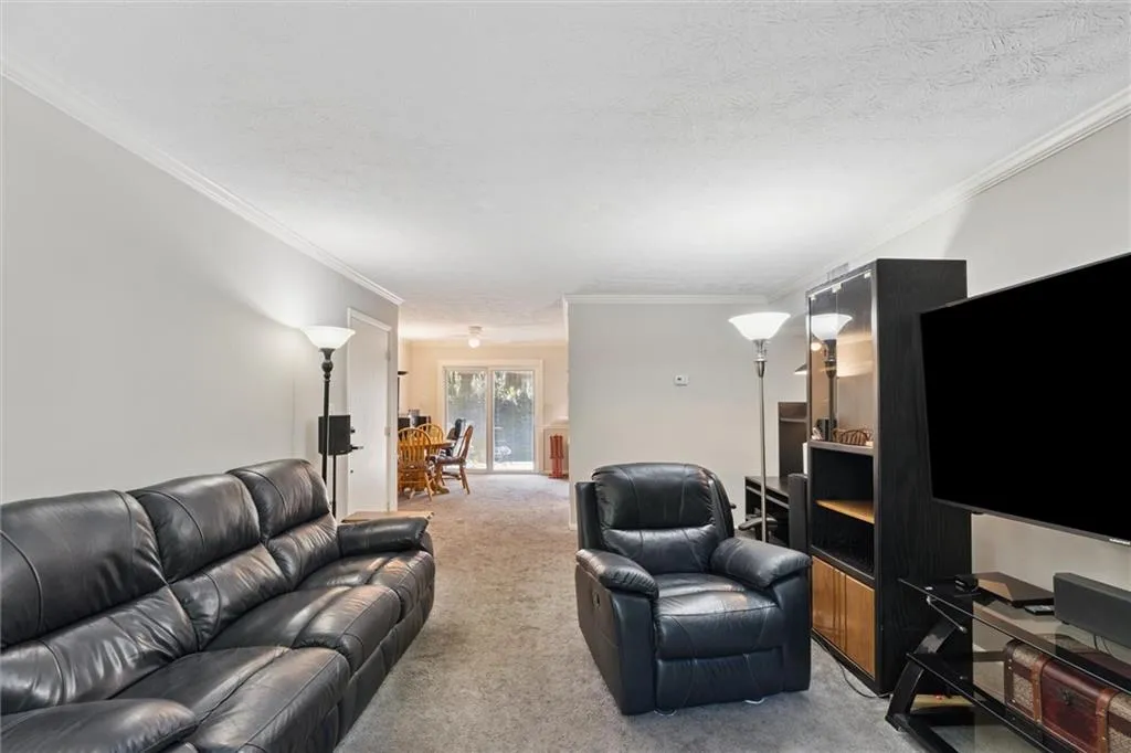 Living area with carpet, ornamental molding, and a textured ceiling