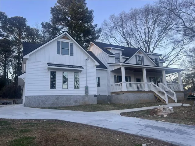 Modern farmhouse style home featuring covered porch, board and batten siding, a shingled roof, and concrete driveway