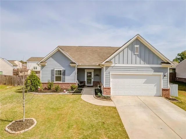 View of front facade with board and batten siding, brick siding, driveway, and an attached garage