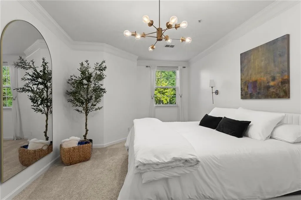 Primary Bedroom with beautiful molding, light carpet, and a chandelier.