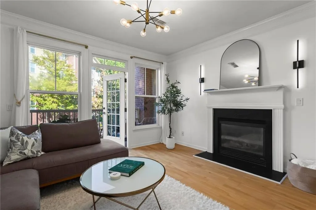Living room featuring crown molding, wood floors, fireplace, and a chandelier.