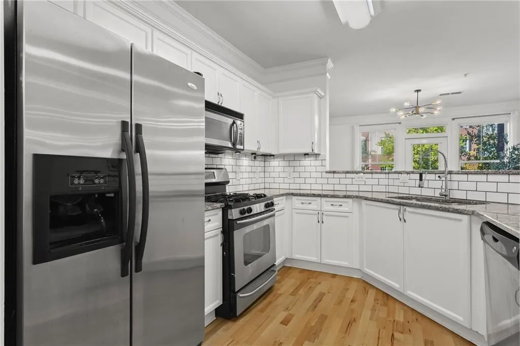 Kitchen with stainless steel appliances, white cabinetry, and stone counters.