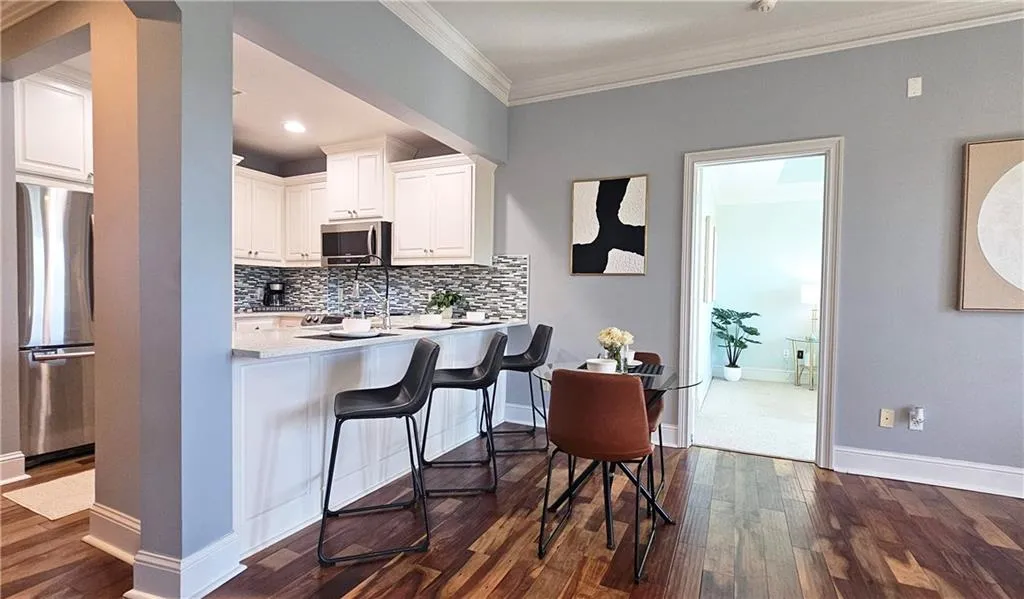 Kitchen with tasteful backsplash, white cabinetry, a breakfast bar, appliances with stainless steel finishes, and dark wood-style flooring