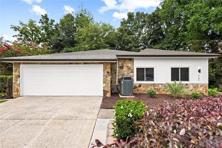Stone facade with a white garage door and white vertical siding