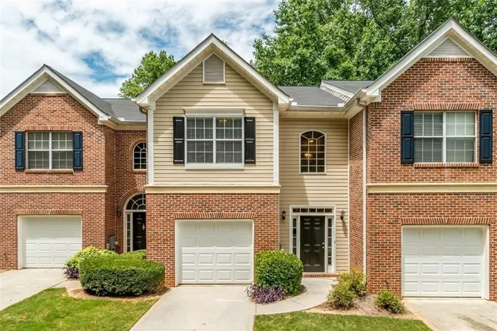 Brick and siding exterior featuring gabled roofs, multiple windows with shutters, and integrated garages