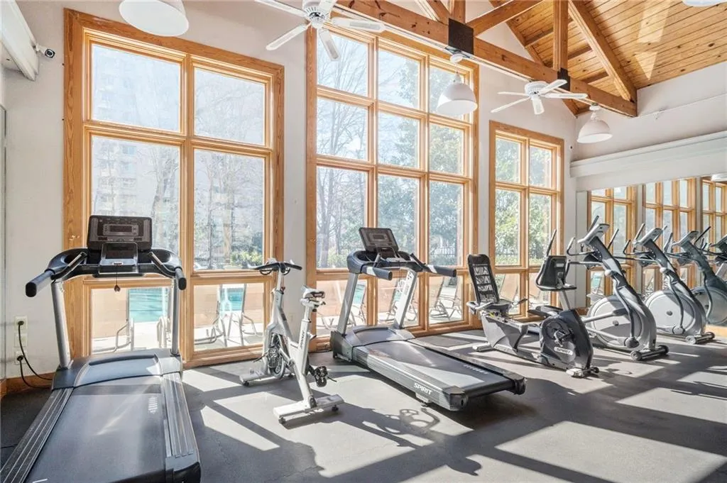 Gym featuring ceiling fan, a wood ceiling with exposed beams, high vaulted ceiling, and healthy amount of natural light