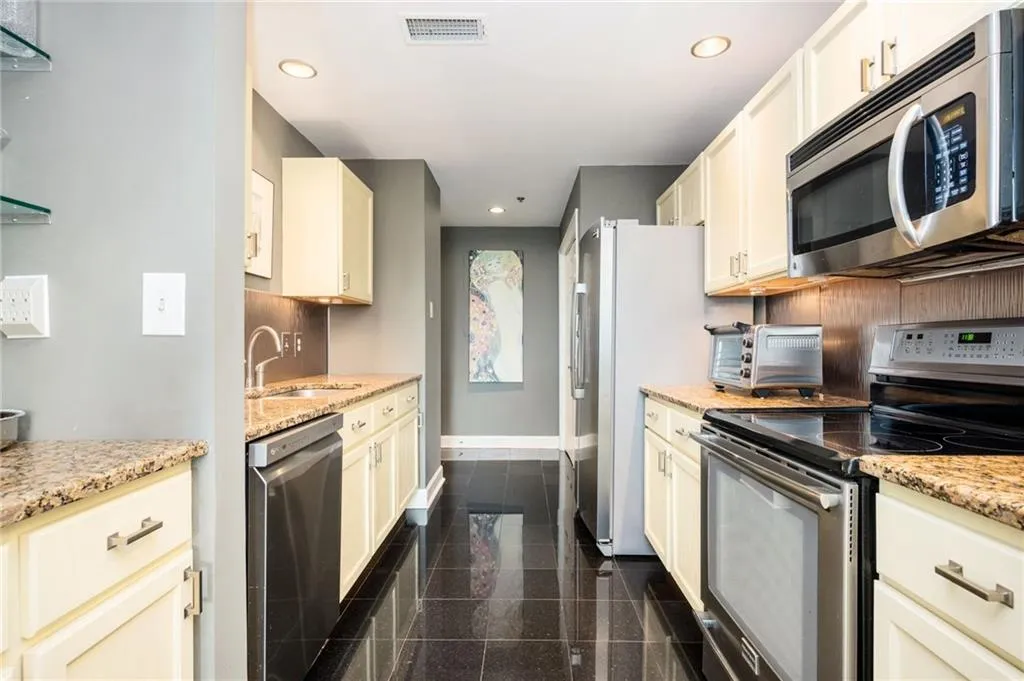 Kitchen featuring stainless steel appliances, granite tiled floors, recessed lighting, backsplash, and light stone counters