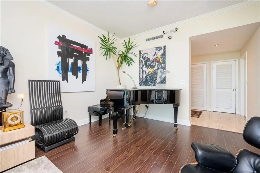 Living area featuring ornamental molding and wood floors large enough for a grand piano