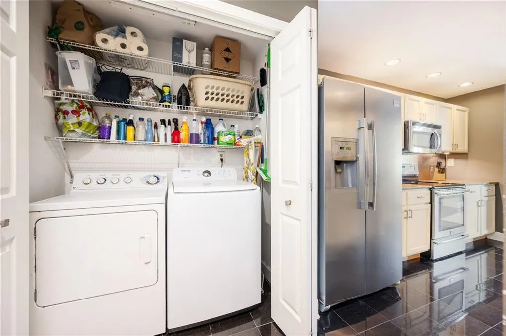 Washroom with washing machine and clothes dryer, granite tiled floors, and recessed lighting