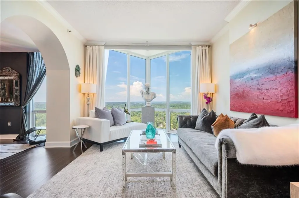 Living area featuring ornamental molding, expansive windows, arched walkways, wood floors, and healthy amount of natural light