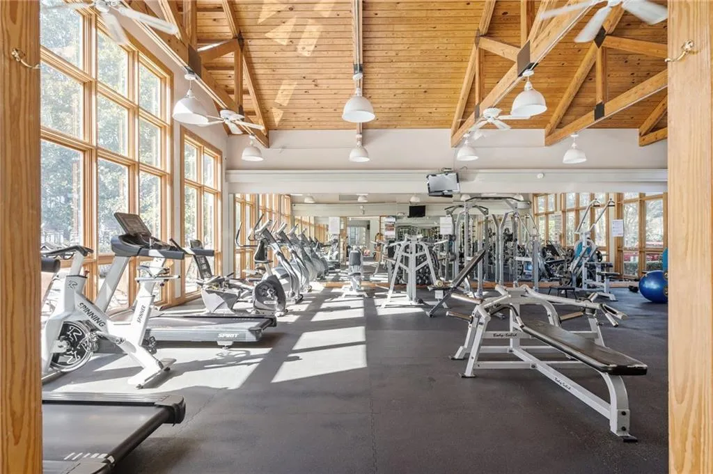 Workout area with a wooden ceiling with exposed beams, plenty of natural light, high vaulted ceiling, and a ceiling fan