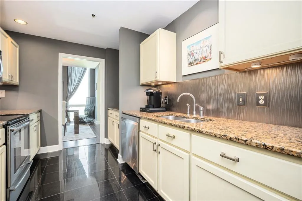 Kitchen with appliances with stainless steel finishes, recessed lighting, granite tiled floors, backsplash, and light stone countertops