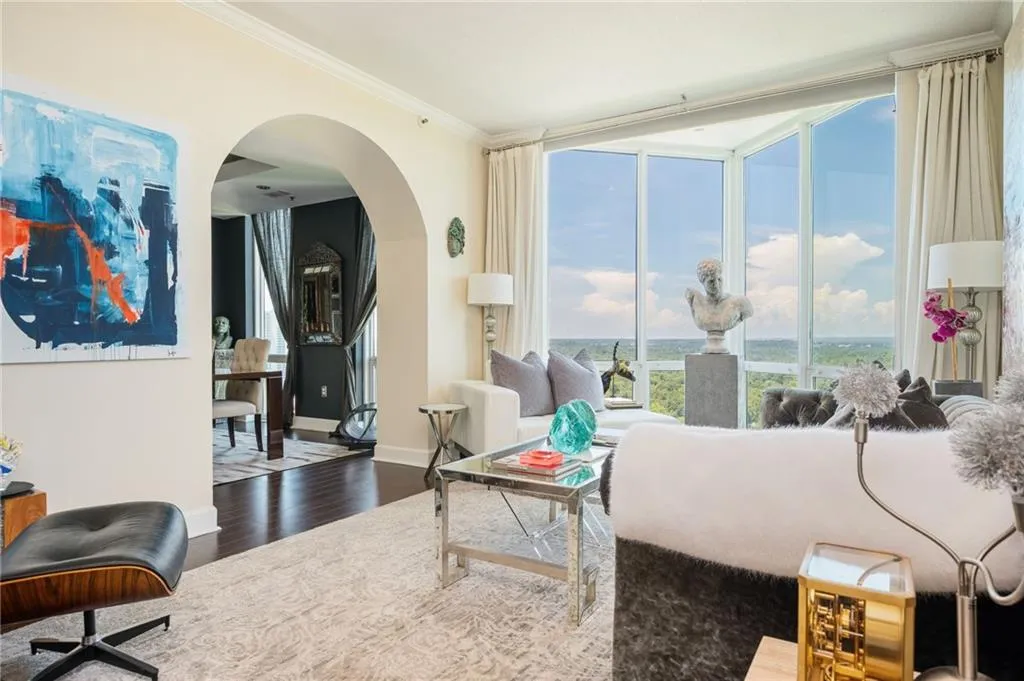 Living room featuring wood floors, arched walkways, expansive windows, and crown molding