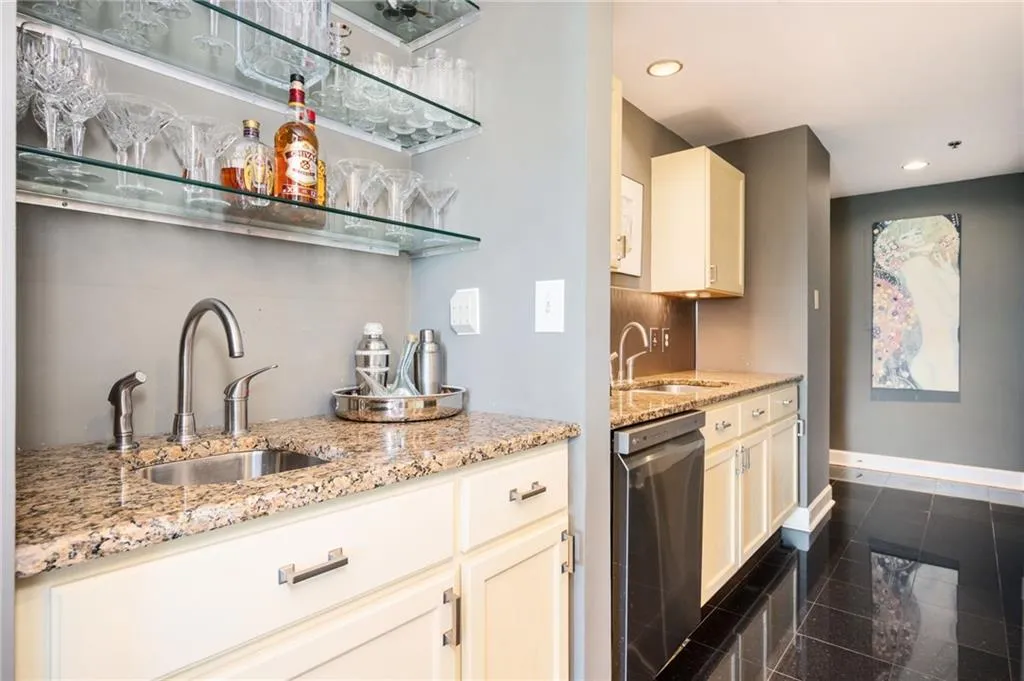 Indoor wet bar featuring stainless steel dishwasher, granite tiled floors, and recessed lighting