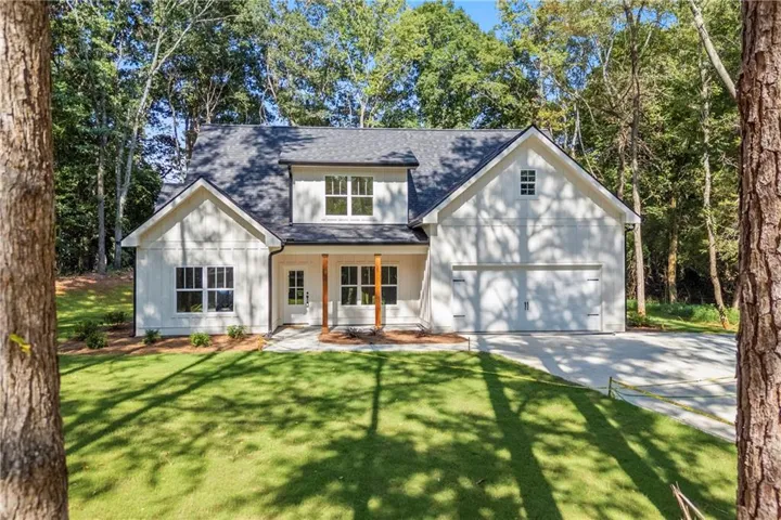 Modern farmhouse exterior with white board and batten siding, dark shingle roofing, and an integrated two-car garage
